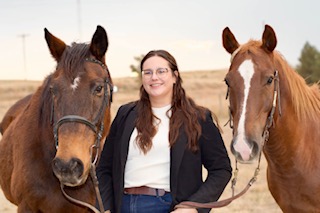 woman posing between two horses 